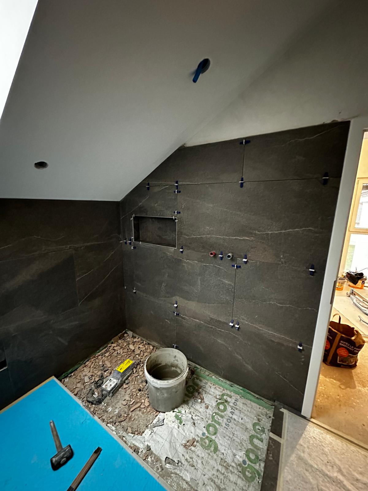 Carrelage mural 60x120 en cours de pose dans la douche sous rampant